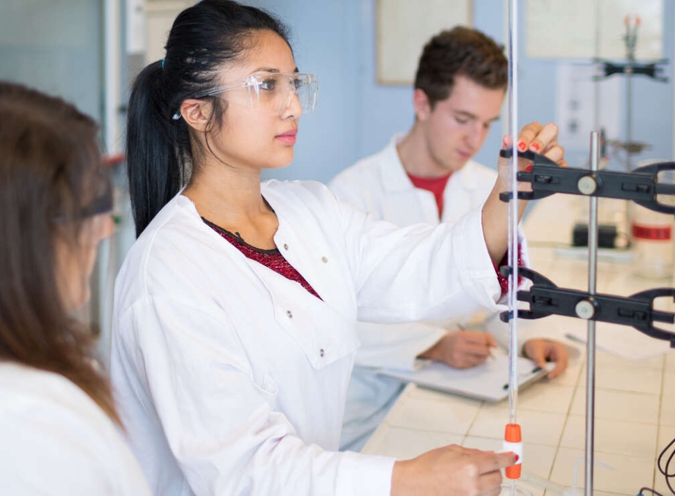 Photo d'une femme portant des lunettes et une blouse de protection, manipulant une pipette